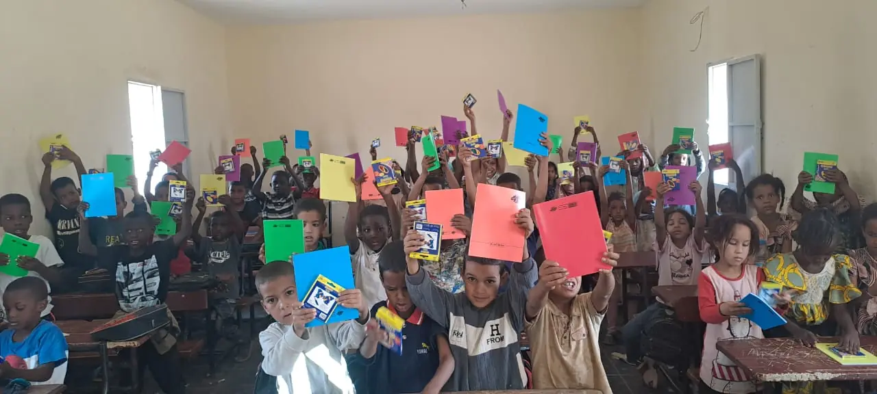 Bambini in classe con i quaderni nuovi alzati